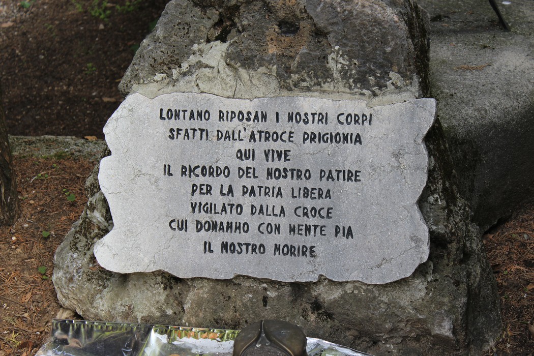 Un monumento in pietra dedicato ai caduti per la libertà, immerso nel verde, con iscrizioni commemorative.