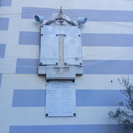 Lapide commemorativa dedicata ai caduti di San Bartolomeo, affissa su una parete colorata.