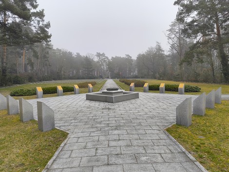 Cimitero militare italiano di Zehlendorf, con monumenti e un'ampia area verde, immerso nella nebbia.