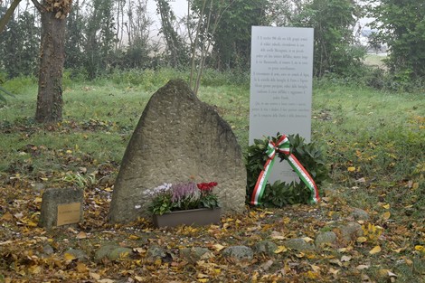 Monumento ai Caduti di Casa Vanti, con pietra e corona di fiori in un contesto naturale autunnale.