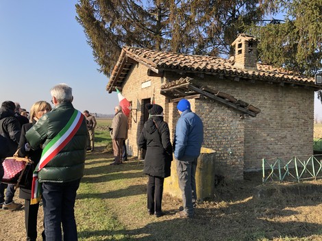 Rappresentazione del Sacrario a Gabetta, con persone in commemorazione e natura circostante.