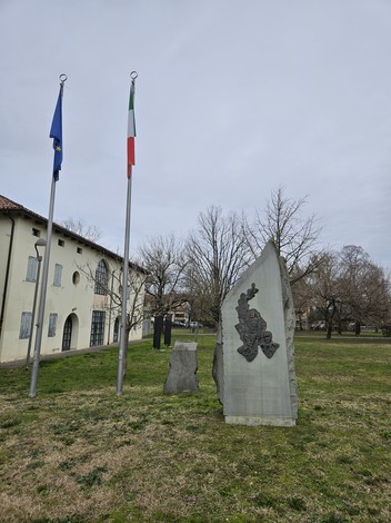 Monumento ai Partigiani con due bandiere e un'area verde circostante, simbolo di memoria storica.