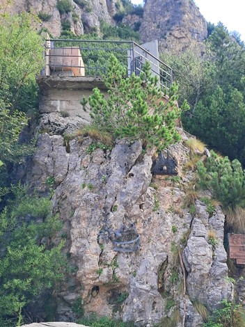 Monumento a Mercante e Dalla Sega, una struttura incastonata nella roccia circondata da vegetazione.