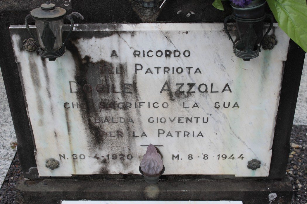 Cippo commemorativo dedicato a Doglio Azzola, eroe patriota, con lanterne e decorazioni.