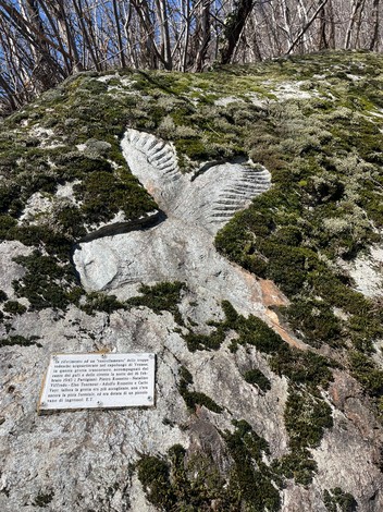 Roccia dei partigiani con scultura incisa e vegetazione circostante su un fondale roccioso.