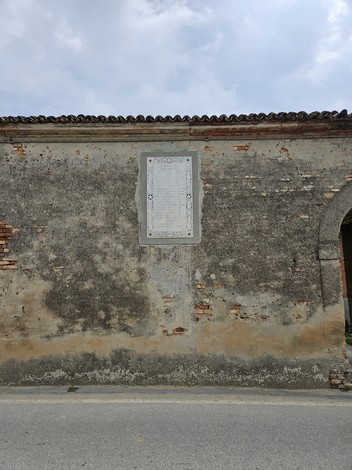 Lapide commemorativa che ricorda i Martiri di Cavezzo, affissa su una parete esterna.