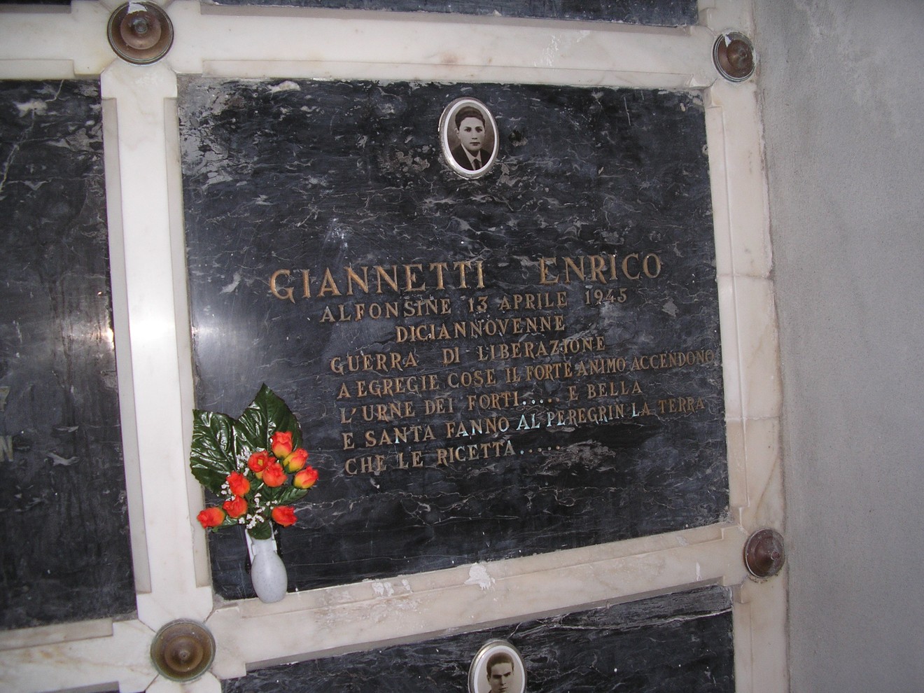 Cappella dei caduti con lapidi commemorative e fiori, simbolo di memoria e rispetto.