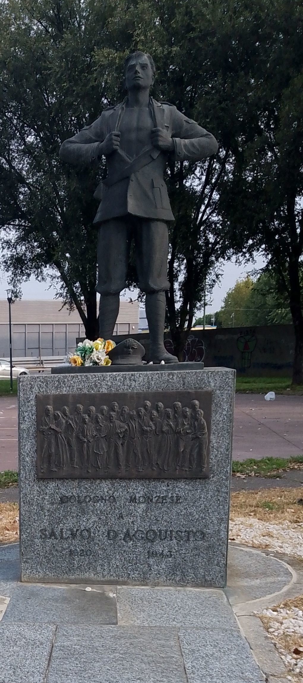 Monumento a D'Acquisto, con una statua che rappresenta un giovane in uniforme, circondato da decorazioni floreali.
