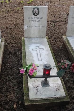 Una tomba con croce e fiori, dedicata a Sebastiano Tizzanini, simbolo di memoria e onore per i caduti.