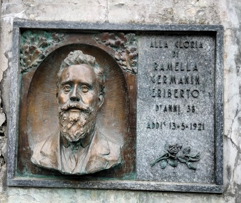 Lapide commemorativa di Ramella Germain, eroe caduto, con riflesso della sua immagine e data di memoria.