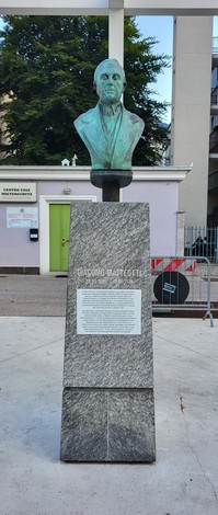 Busto bronzeo di Giacomo Matteotti su monumento in pietra, situato in un'area urbana.