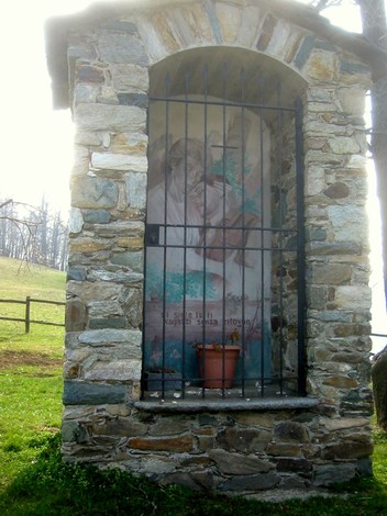 Rifugio caratteristico con affresco in pietra, immerso nel verde della natura montana.