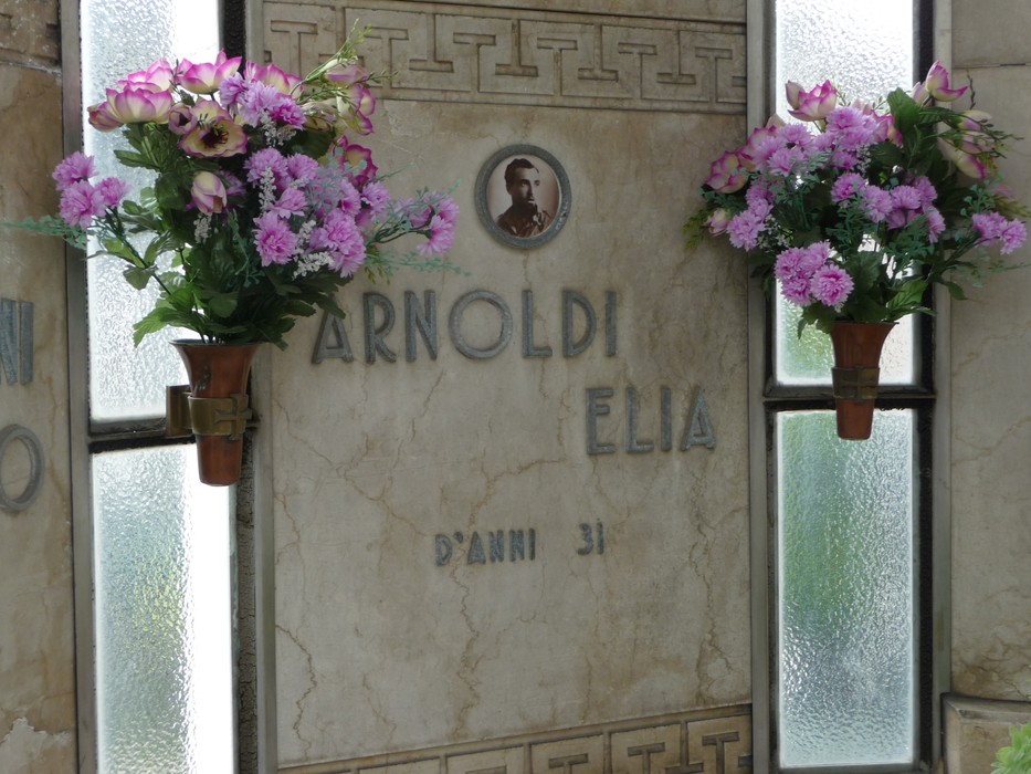 Sacrario dedicato ai caduti partigiani, con fiori e targa commemorativa di un caduto.