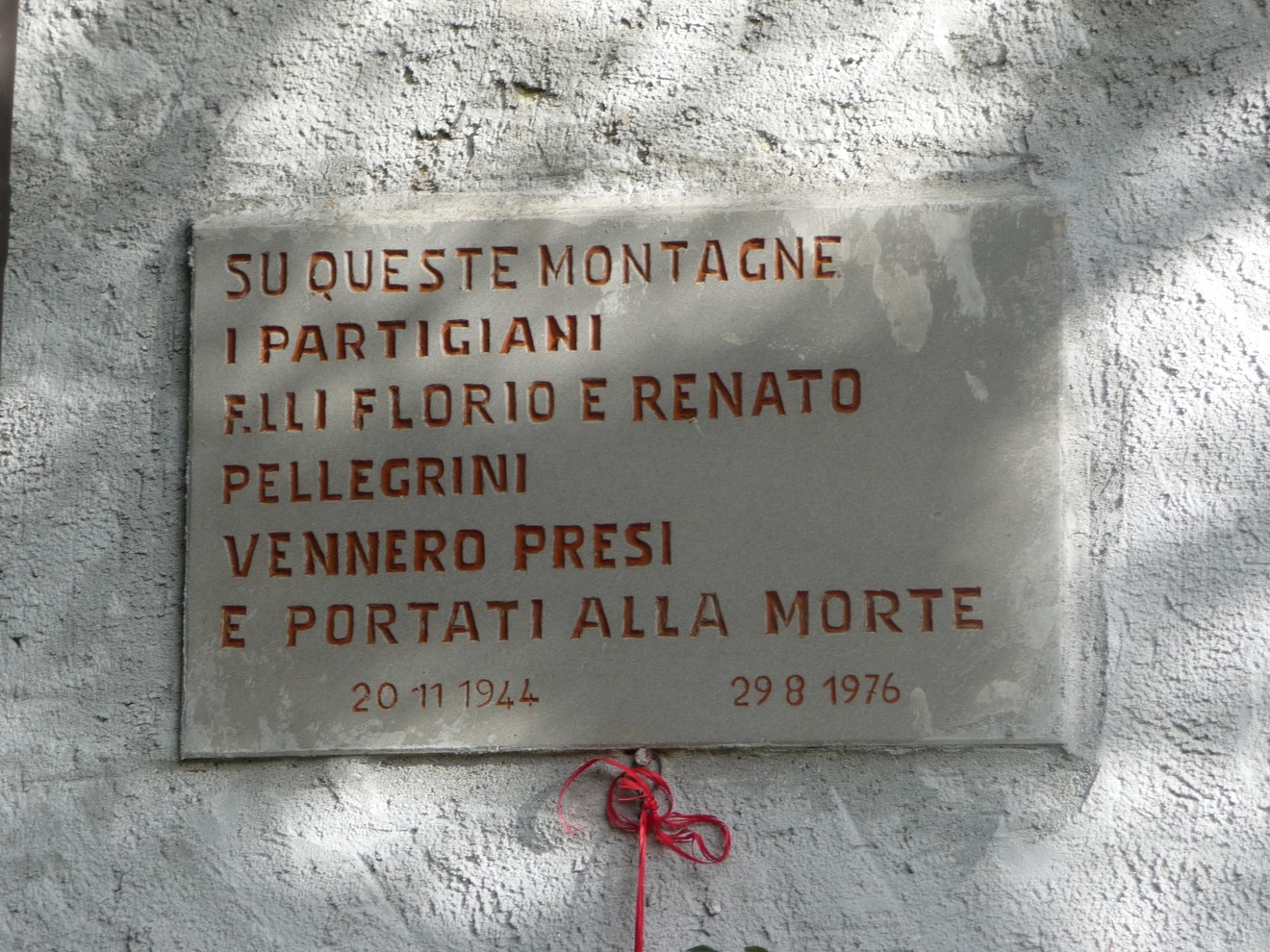 Lapide commemorativa dedicata ai fratelli Pellegrini, partigiani, situata su una montagna.