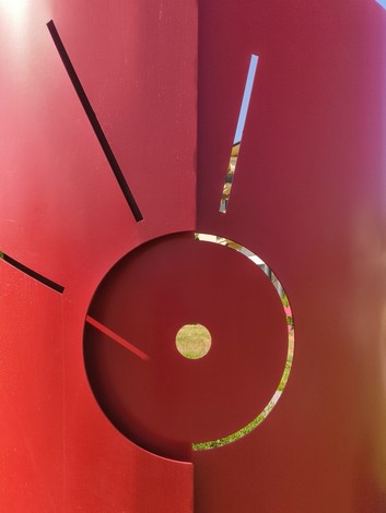Scultura rossa con forme circolari e lineari che suggeriscono dinamismo e resistenza femminile.