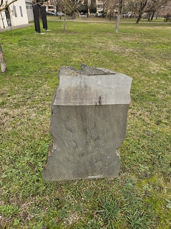 Monumento ai Partigiani, una pietra commemorativa in un parco, circondata da vegetazione.
