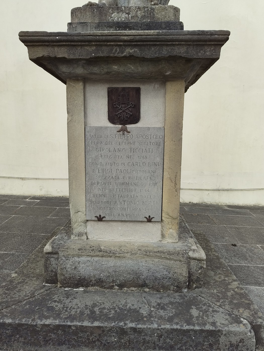 Lapide commemorativa per il danneggiamento della statua a San Pietro, su base in pietra con stemma papale.
