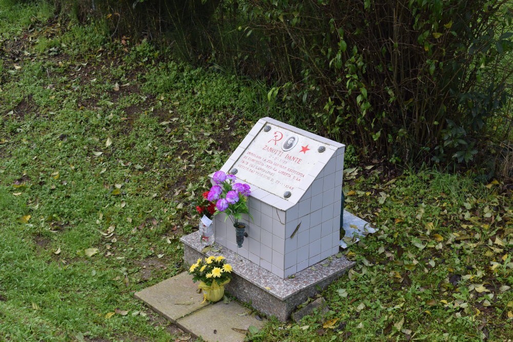 Cippo commemorativo con fiori in una zona verde, dedicato a Zanotti. Memoria e ricordo in un contesto naturale.