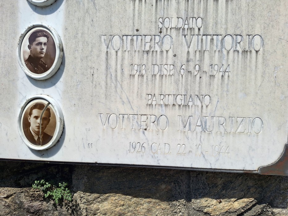Lapide commemorativa dedicata ai caduti in guerra, con fotografie e nomi di soldati.