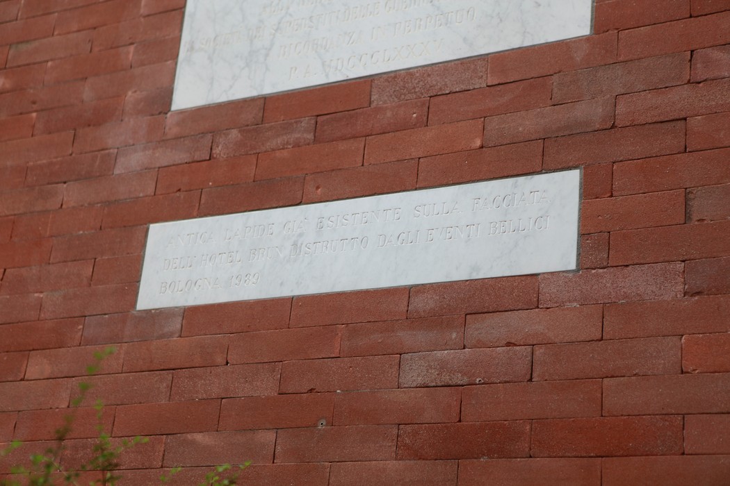 Lapide commemorativa su un muro di mattoni, simbolo di memoria e riconciliazione storica.