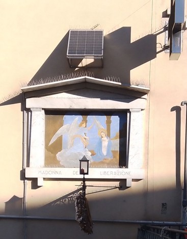 Immagine della Madonna della Liberazione, affresco su muro con angelo e figura mariana in un contesto urbano.