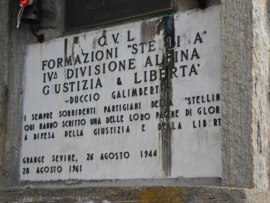 Targa in marmo con iscrizione, murata su una parete in pietra, dedicata alla formazione partigiana Stellina.