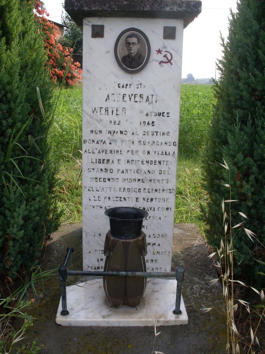 Cippo in memoria di Asseverati, dedicato ai caduti della guerra, con simboli e iscrizioni commemorative.