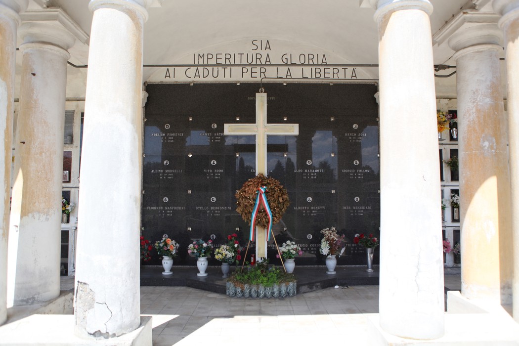 Sacrario commemorativo con croce, fiori e iscrizioni per i caduti in nome della libertà.