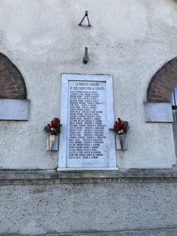 Lapide commemorativa ai caduti di Leumann, decorata con fiori, in onore dei sacrifici durante il conflitto.