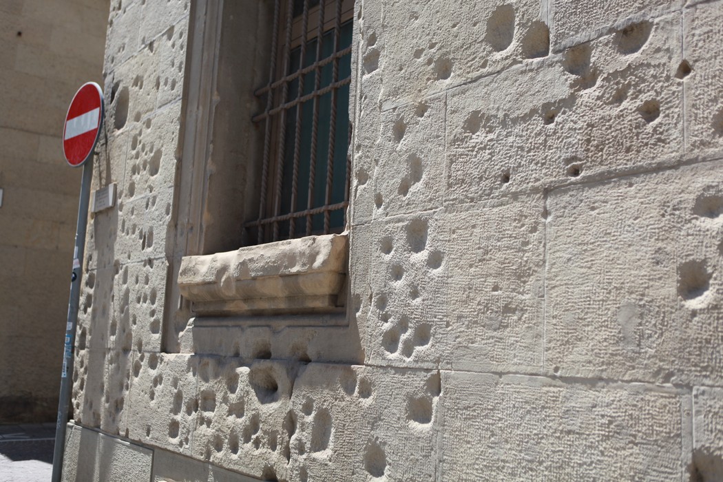Lapide commemorativa dei danni causati dal bombardamento del 24 luglio 1943, con segni visibili sulla facciata.