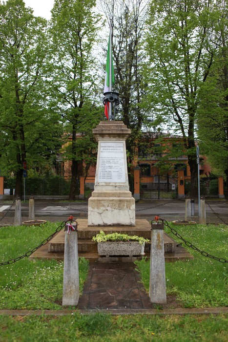 Monumento ai caduti per la Libertà, circondato da alberi e decorato con una bandiera tricolore.