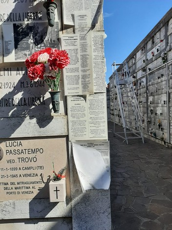 Viste di un cimitero con loculi, fiori rossi e pannelli commemorativi dei martiri della libertà.