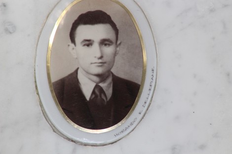 Ritratto di un giovane in bianco e nero, incassato in una cornice ovalizzata su sfondo di marmo.