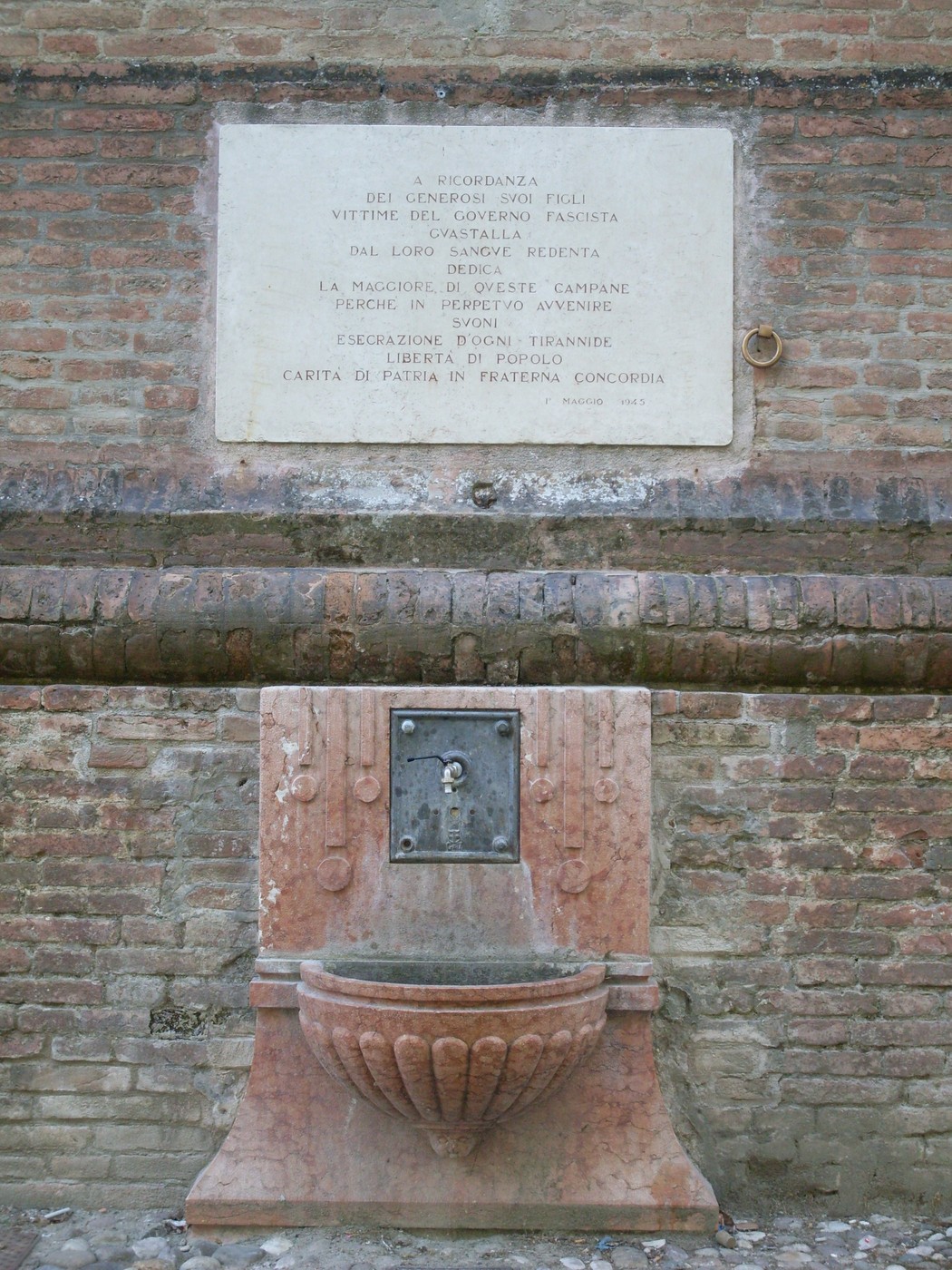 Lapide commemorativa dedicata alle vittime del regime fascista, posta su una muratura in mattoni.