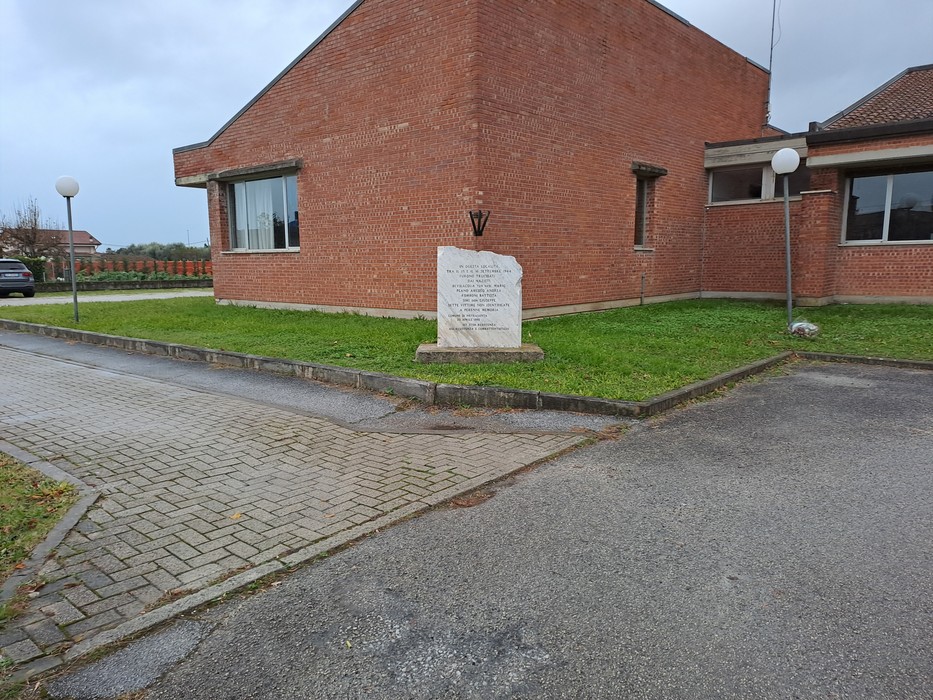 Monumento ai caduti di Osterietta, situato accanto a un edificio, circondato da verde e strada.