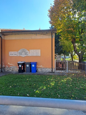 Lapidi commemorative in un'area all'aperto, circondata da alberi e spazi verdi.