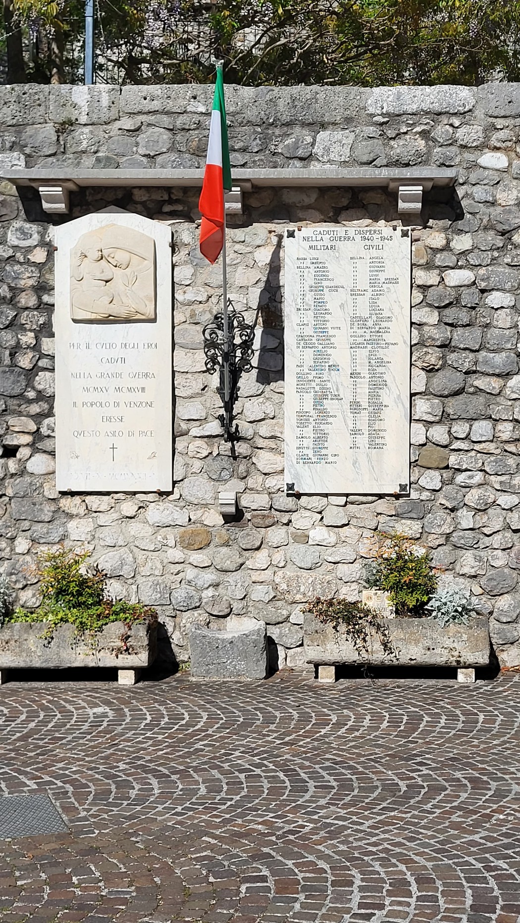 Lapide commemorativa dedicata ai caduti della guerra 1940-1945 con bandiera italiana e listino nomi su pietra.
