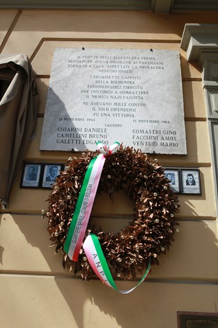 Lapide commemorativa dedicata ai caduti della battaglia della Bolognina, adornata da una corona di fiori.