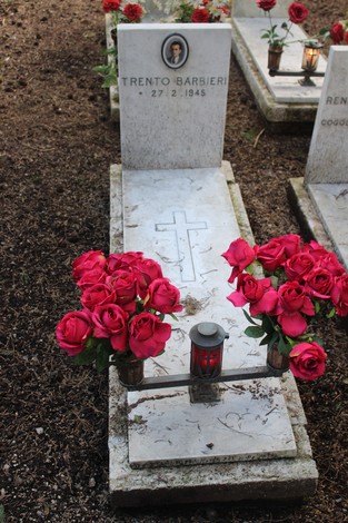 Tombe di caduti per la libertà decorate con rose rosse, simbolo di rispetto e memoria.