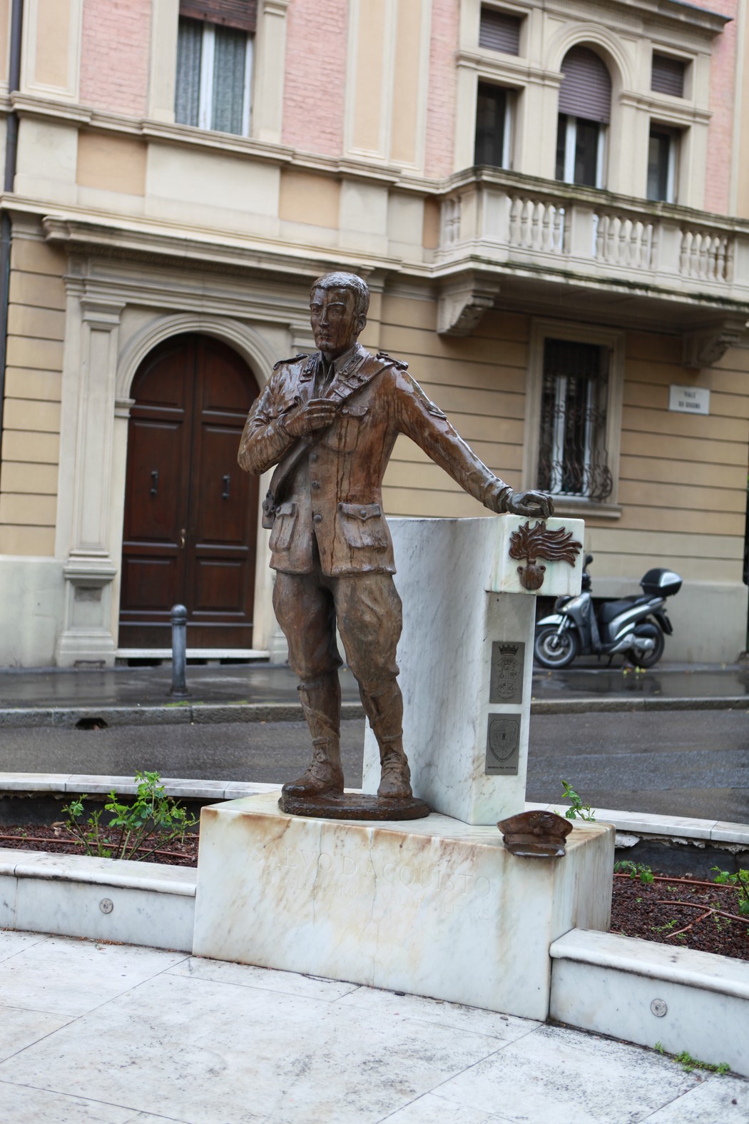 Monumento a D'Acquisto, statua in bronzo di un giovane uomo in uniforme con un'aquila, in un contesto urbano.