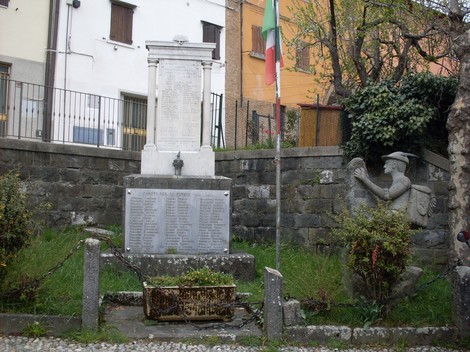Monumento ai Caduti di Collagna, dedicato ai soldati della comunità, situato in un'area verde con bandiera.
