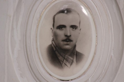 Ritratto in bianco e nero di un uomo, con uno sguardo serio e una sciarpa, incorniciato in un ovalino bianco.