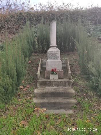 Cippo commemorativo a Ceconato, circondato da piante e scalini che conducono alla base.
