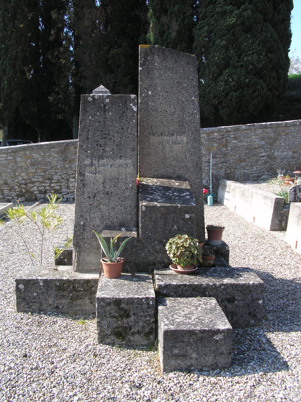Sepolcro commemorativo dedicato ai caduti del Palazzaccio, immerso in un giardino di pietra e vegetazione.