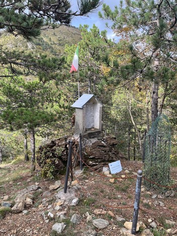 Sacrario ai Martiri di Passo Mezzano, monumento commemorativo immerso nel verde montano, circondato da alberi e storia.