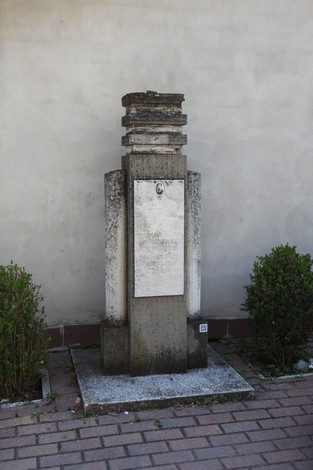 Cippo a Raimondi, monumento in pietra con base quadrata e superficie liscia, circondato da piccole piante.